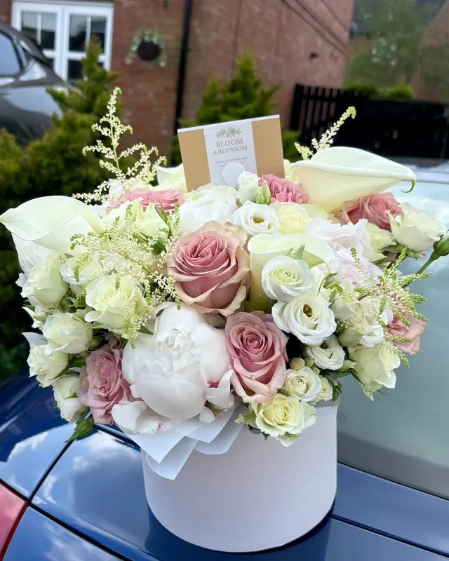 Blush roses and lisianthus in a white hat box